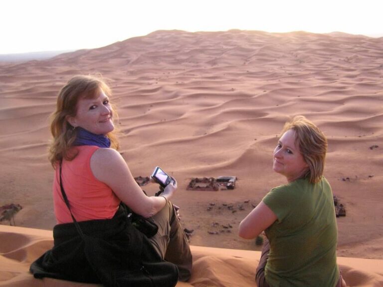 Two travellers standing on sand dunes in the Moroccan desert